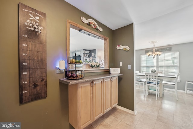 bar featuring baseboards, light tile patterned floors, and a chandelier