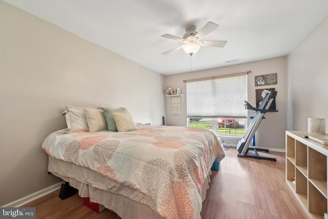 bedroom featuring a ceiling fan, baseboards, visible vents, and wood finished floors