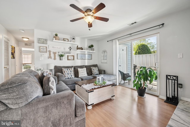 living room featuring visible vents, light wood finished floors, and ceiling fan