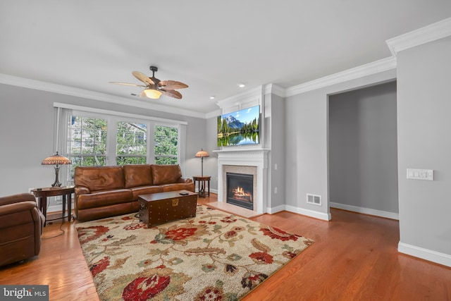 living room featuring visible vents, ornamental molding, baseboards, and a glass covered fireplace
