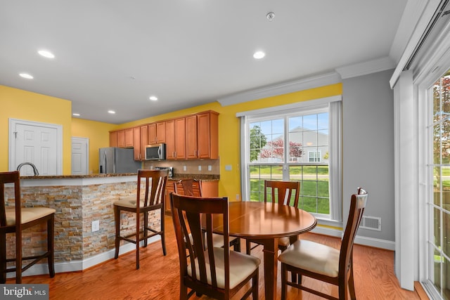 dining space with crown molding, recessed lighting, and light wood finished floors