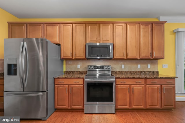 kitchen with brown cabinetry, stainless steel appliances, and light wood-type flooring