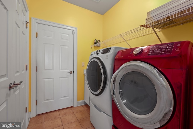 laundry area featuring baseboards, laundry area, washer and clothes dryer, and tile patterned floors
