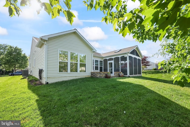 rear view of property with a lawn, a sunroom, and cooling unit