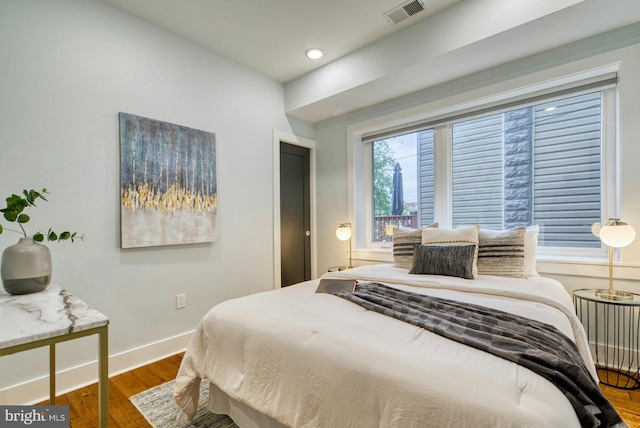 bedroom with wood finished floors, baseboards, and recessed lighting