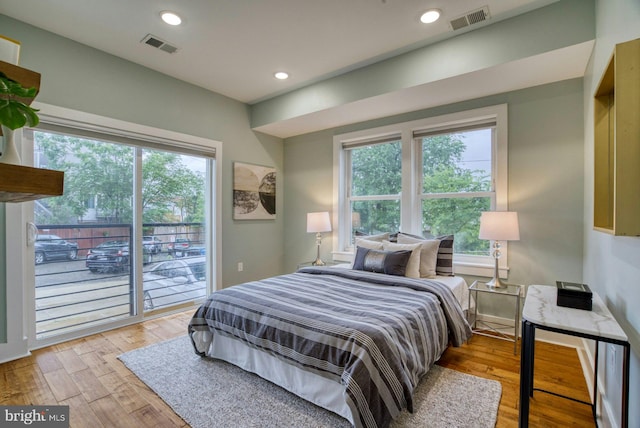bedroom with access to outside, multiple windows, light wood finished floors, and recessed lighting