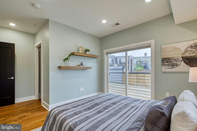 bedroom with wood finished floors, baseboards, recessed lighting, and access to outside