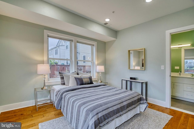 bedroom with baseboards, wood finished floors, recessed lighting, a sink, and ensuite bathroom