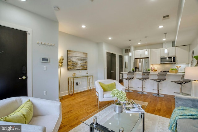 living area with recessed lighting, light wood-style flooring, and baseboards
