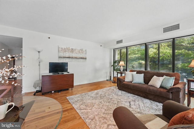 living room featuring visible vents, plenty of natural light, and wood finished floors
