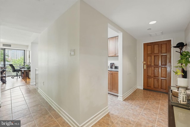 hallway featuring light tile patterned floors, baseboards, and visible vents