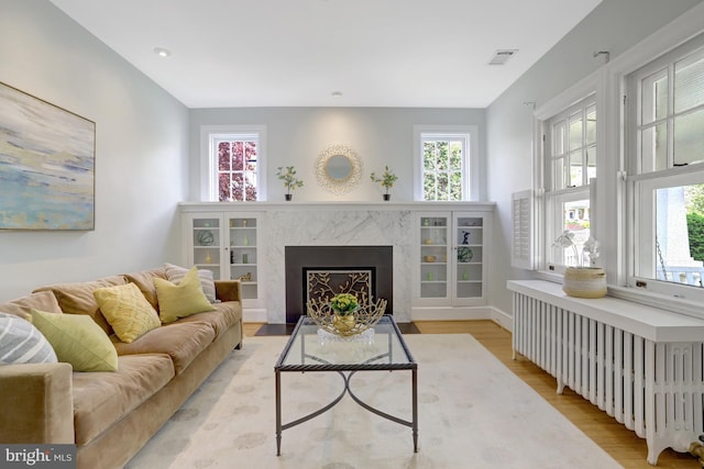 living room featuring visible vents, a wealth of natural light, radiator heating unit, and light wood finished floors