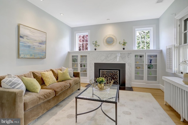 living area featuring radiator heating unit, visible vents, wood finished floors, and a premium fireplace