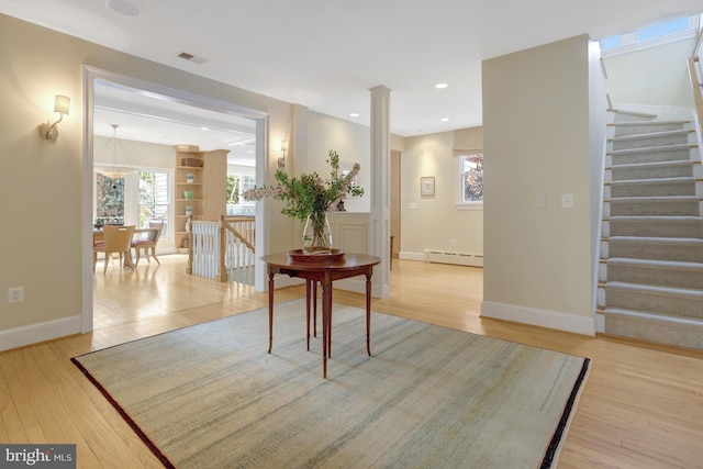 hall with light wood-style flooring, baseboards, a baseboard radiator, visible vents, and stairway