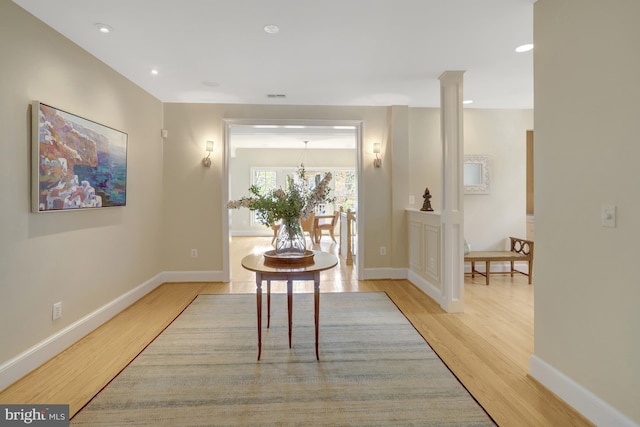 corridor featuring baseboards, a chandelier, visible vents, and light wood-type flooring