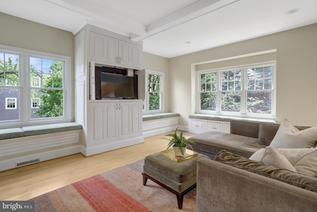 living area featuring visible vents, beam ceiling, and light wood-style floors