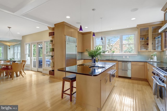 kitchen featuring a warming drawer, high end appliances, a sink, and light wood finished floors