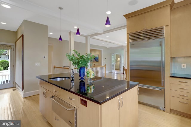 kitchen featuring light brown cabinetry, built in refrigerator, a sink, and a warming drawer
