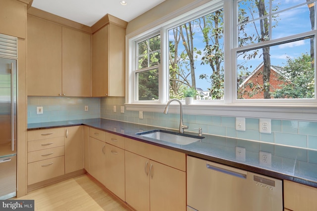 kitchen featuring tasteful backsplash, a sink, light wood-style floors, light brown cabinets, and stainless steel appliances
