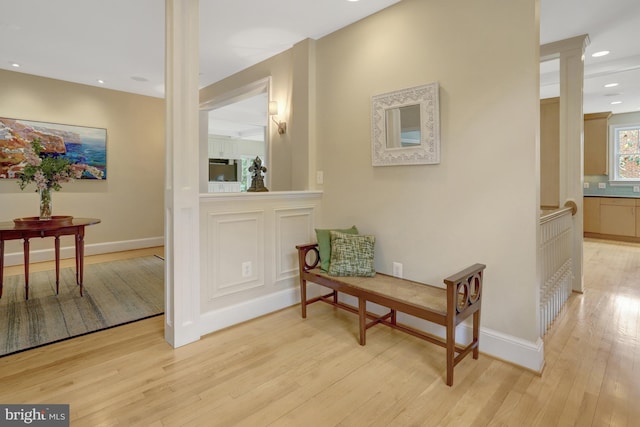 corridor featuring light wood-style floors, baseboards, decorative columns, and recessed lighting