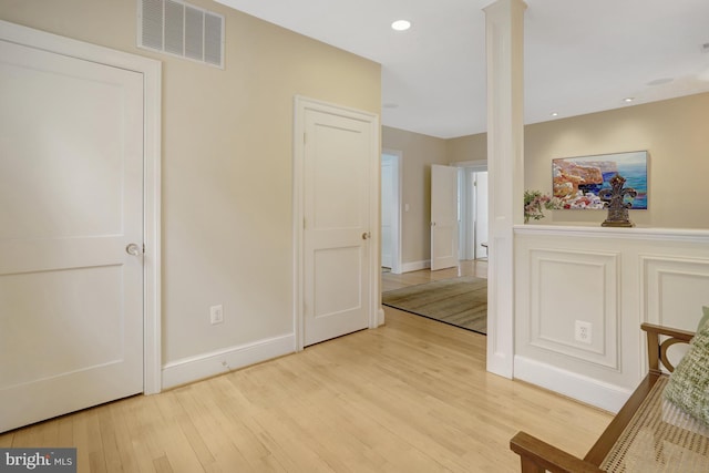 interior space featuring visible vents, baseboards, decorative columns, and light wood-type flooring