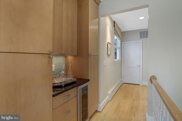 interior space with visible vents, dark countertops, beverage cooler, light wood-type flooring, and a baseboard heating unit