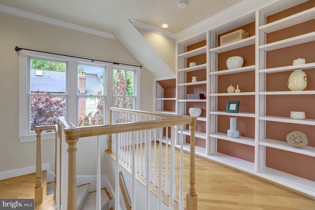 hallway featuring crown molding, baseboards, an upstairs landing, and light wood-style flooring