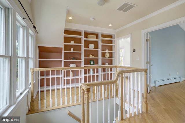 corridor with visible vents, ornamental molding, wood finished floors, baseboard heating, and an upstairs landing