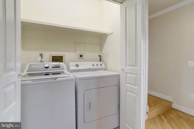 laundry area with laundry area, crown molding, baseboards, light wood-type flooring, and washer and clothes dryer