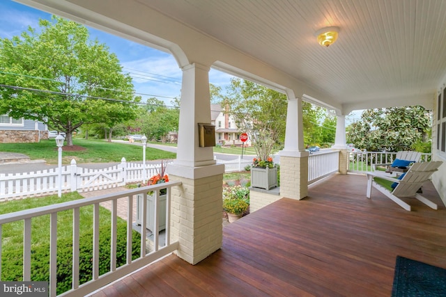 wooden deck with covered porch, a yard, and fence