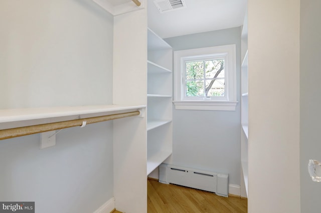 walk in closet featuring a baseboard heating unit, light wood finished floors, and visible vents