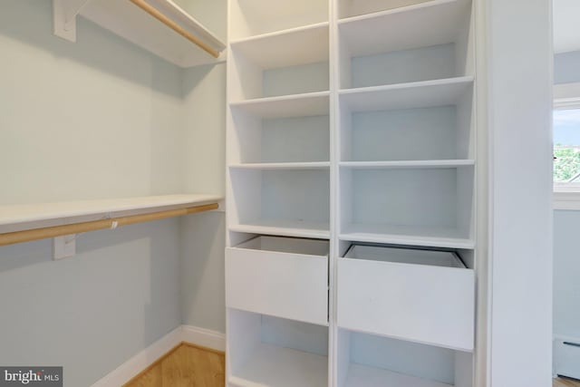 spacious closet featuring a baseboard heating unit and light wood-type flooring