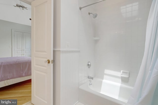 ensuite bathroom with ensuite bathroom, shower / bath combo with shower curtain, and wood finished floors