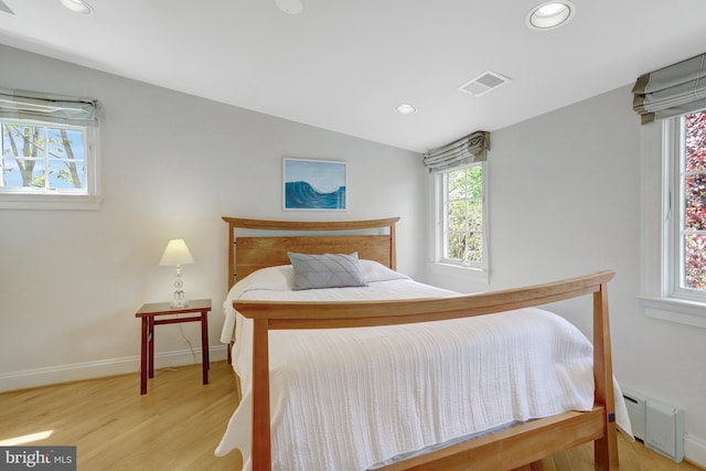 bedroom with baseboards, recessed lighting, wood finished floors, and visible vents