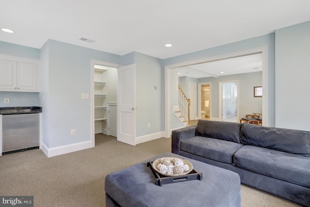 living room featuring visible vents, stairs, baseboards, recessed lighting, and light colored carpet