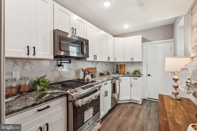 kitchen featuring stainless steel appliances, dark stone countertops, and white cabinetry