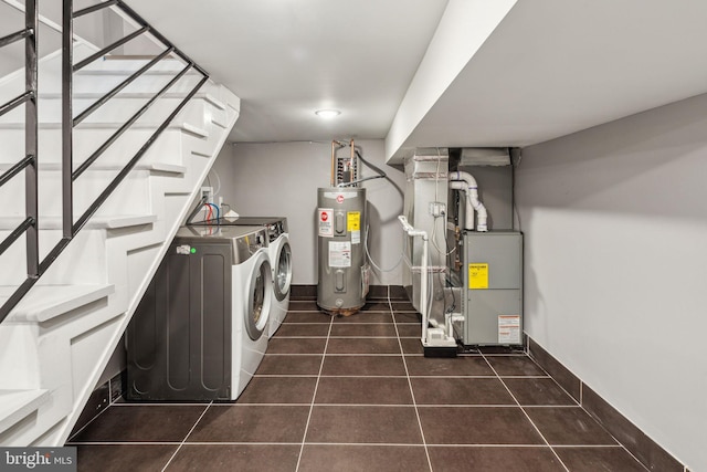 washroom featuring laundry area, tile patterned flooring, washing machine and dryer, baseboards, and electric water heater