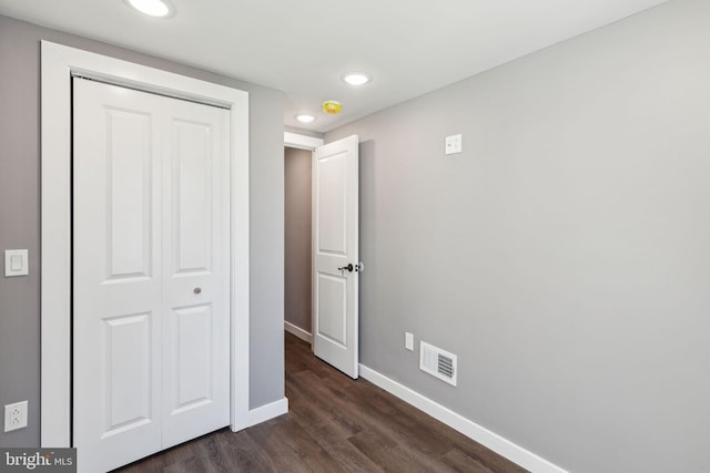 unfurnished bedroom featuring recessed lighting, baseboards, dark wood-type flooring, visible vents, and a closet
