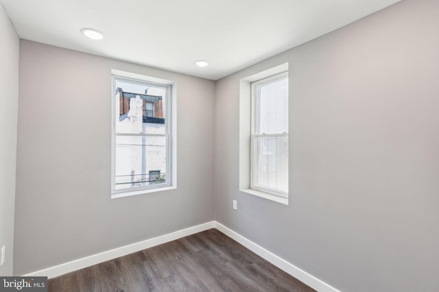 spare room with baseboards, dark wood finished floors, and plenty of natural light