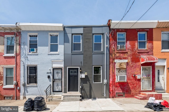 townhome / multi-family property featuring brick siding, cooling unit, and entry steps