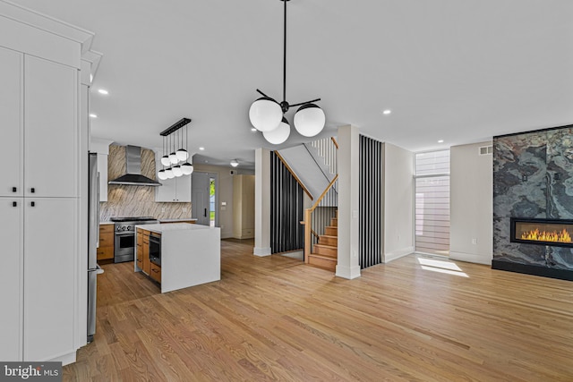 300 Ewing St, Princeton, NJ 08540 - kitchen with wall chimney range hood, open floor plan, stainless steel appliances, light wood-type flooring, and white cabinets