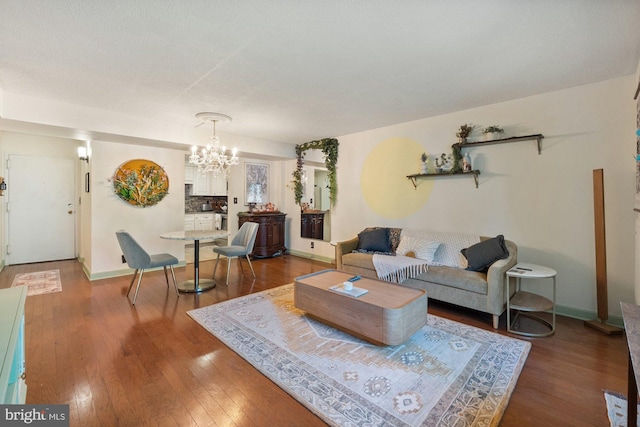 living area with baseboards, wood finished floors, and a chandelier