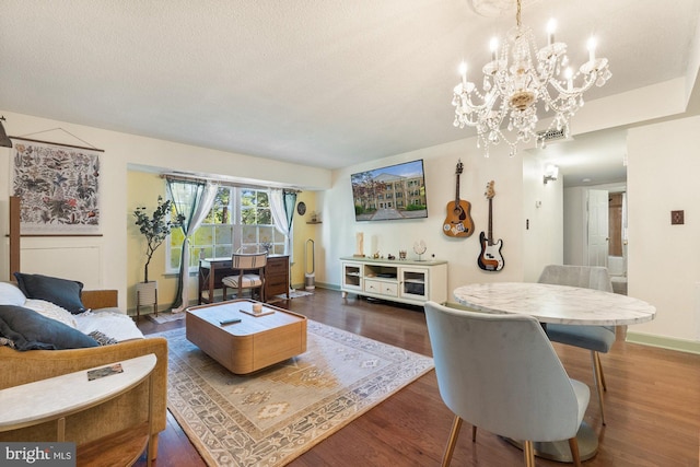 living room featuring baseboards, wood finished floors, and a notable chandelier