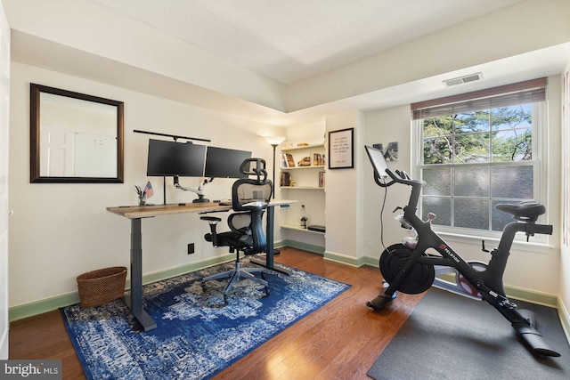 workout area with baseboards, wood finished floors, and visible vents