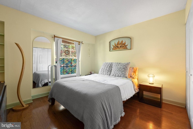 bedroom with baseboards, wood finished floors, and a closet
