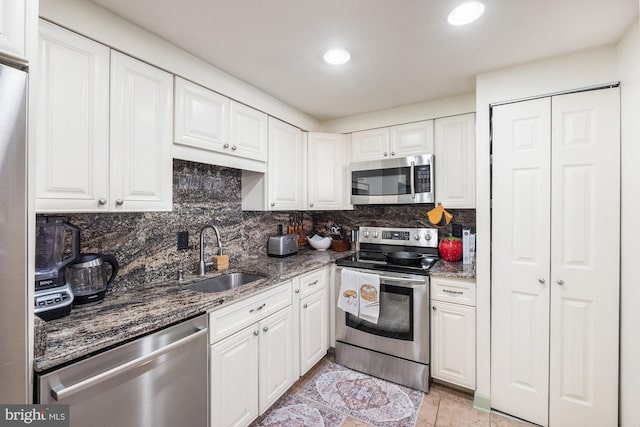 kitchen featuring white cabinets, appliances with stainless steel finishes, decorative backsplash, and a sink