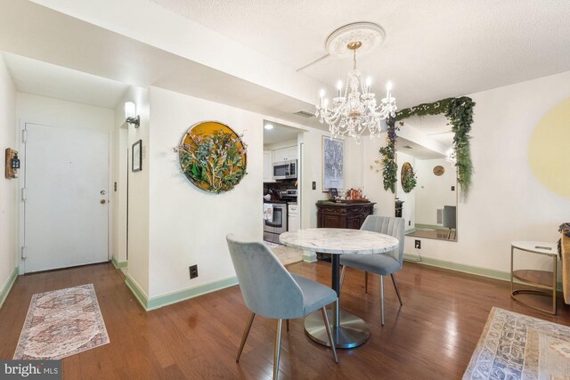 dining room with baseboards, wood finished floors, a notable chandelier, and visible vents
