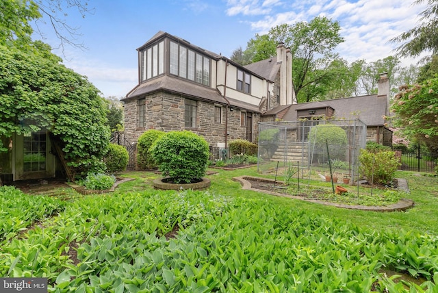 8300 Cedar Rd, Elkins Park, PA 19027 - rear view of house featuring a chimney, fence, a garden, and stone siding