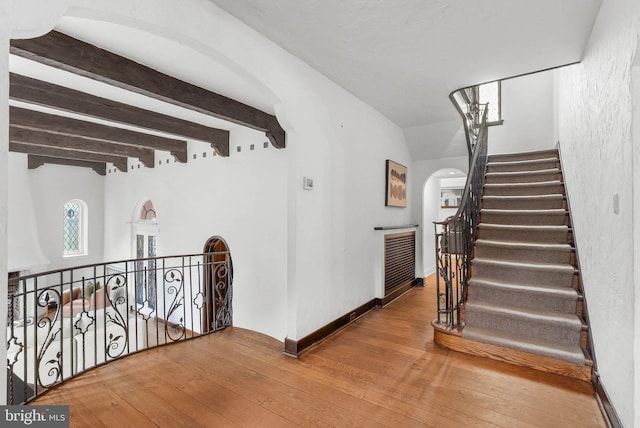 8300 Cedar Rd, Elkins Park, PA 19027 - stairs featuring beam ceiling, baseboards, wood-type flooring, and arched walkways