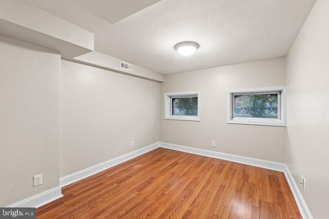 below grade area with visible vents, wood finished floors, and baseboards